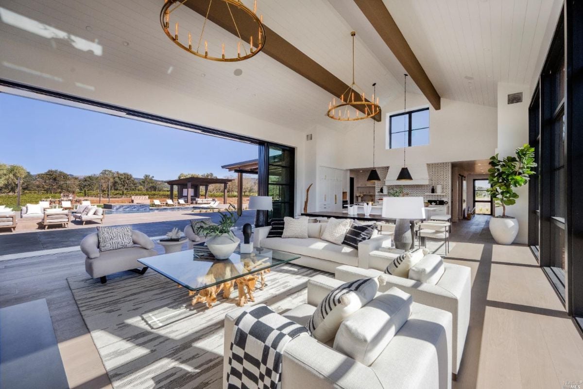 Living room with couches, Cathedral ceiling, oak wood floors, and a huge glass windows.