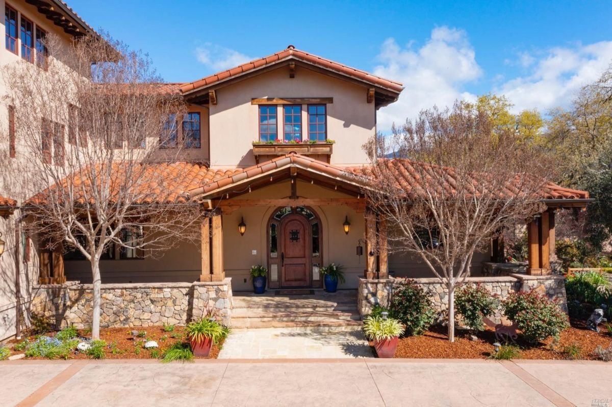 Formal entry of the mansion with a large front yard and a driveway.
