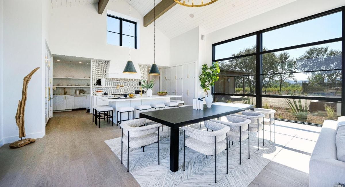 Dining room with large glass windows, Cathedral ceiling and a table.