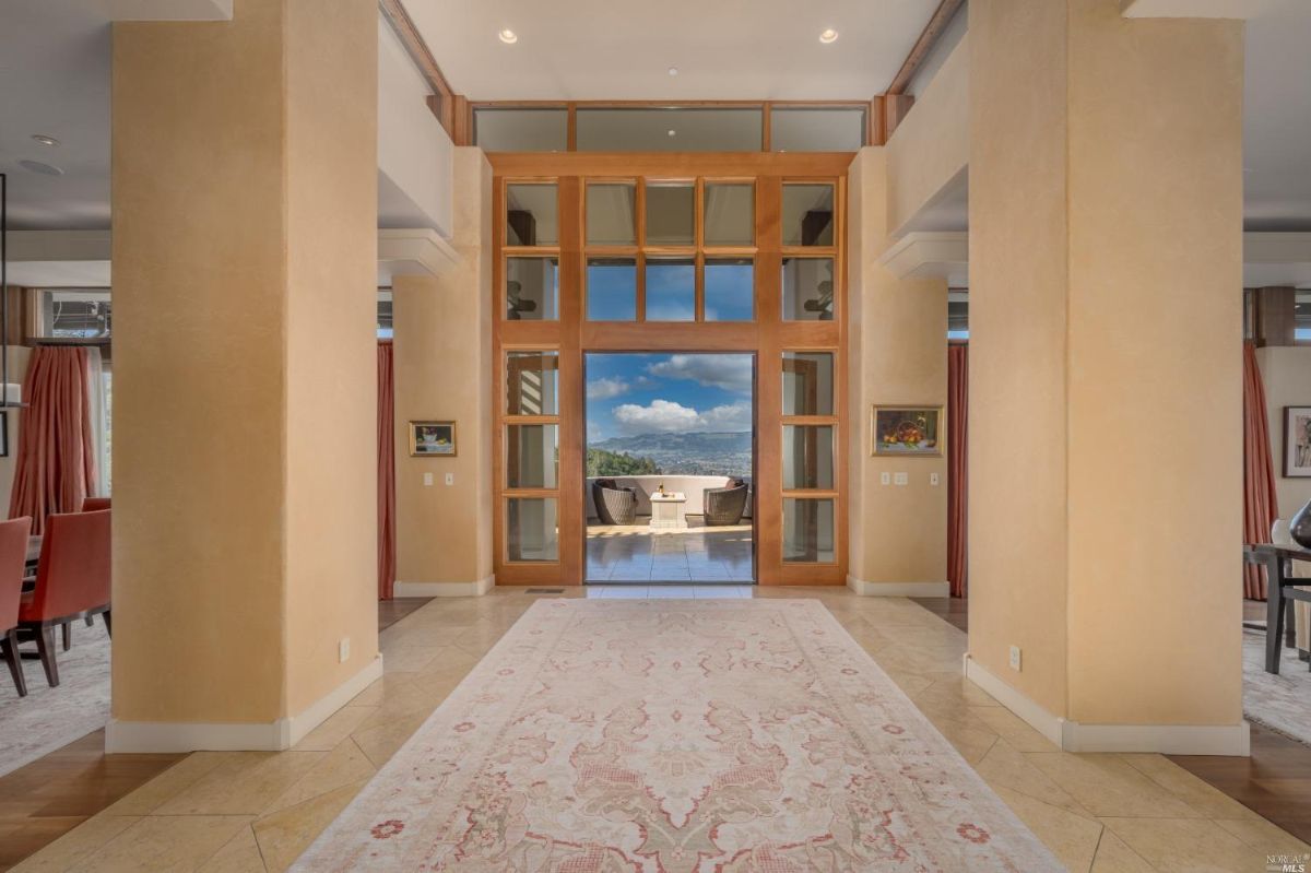 Foyer with a large carpet and custom wood & glass doors.
