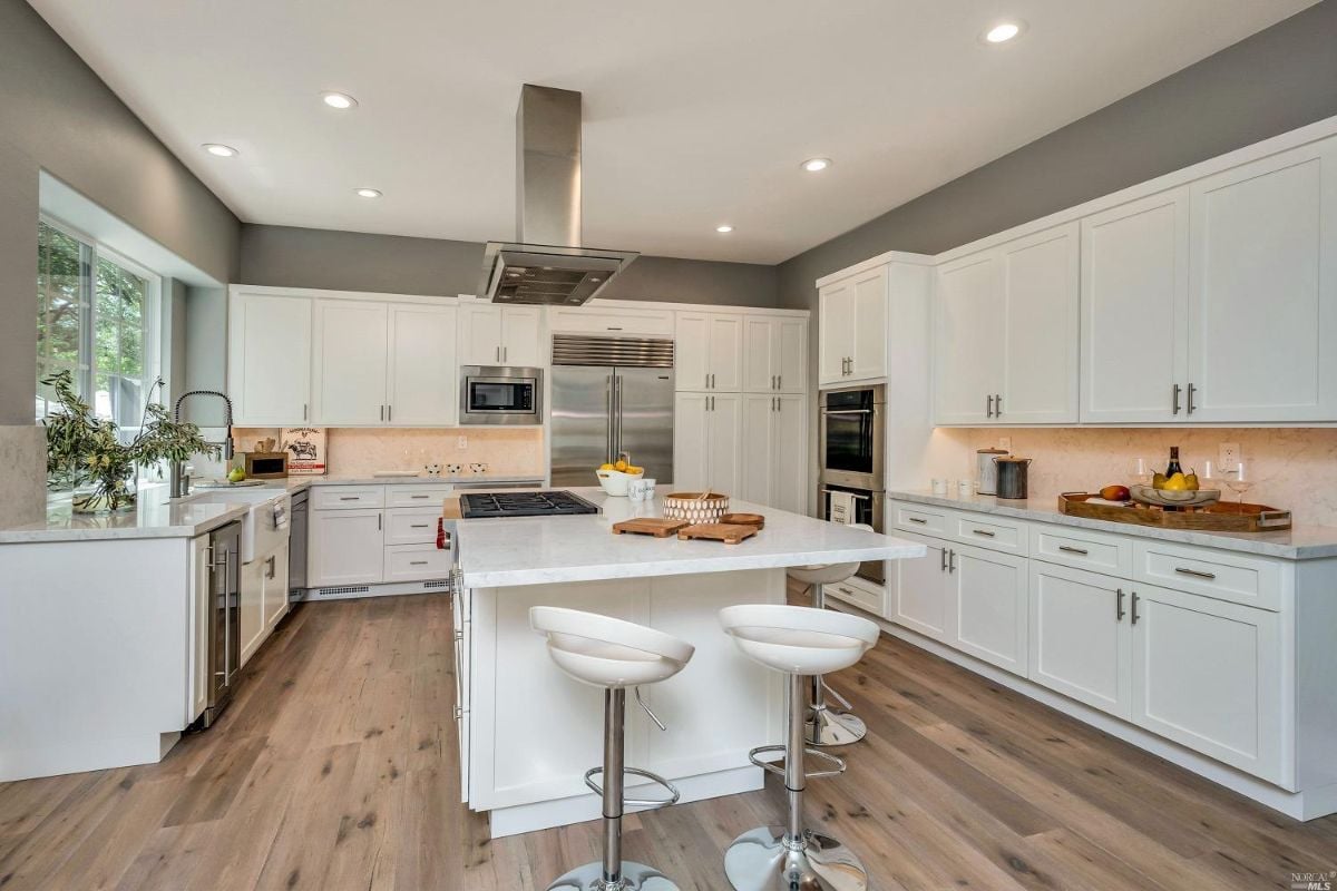 Kitchen with wood flooring, white cabinets and a large island.