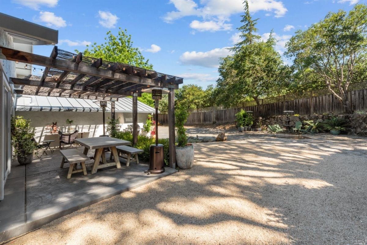 Pergola with wooden table and chairs.