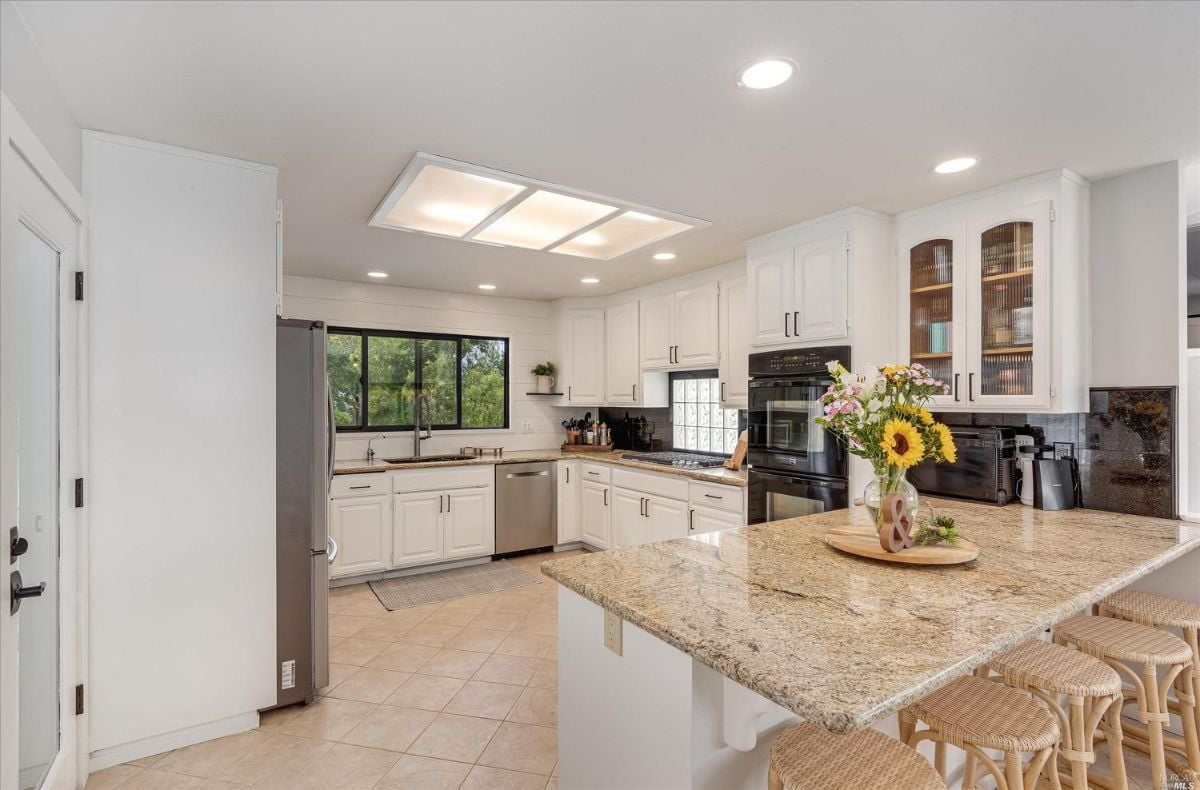 Kitchen with tile flooring, skylights, and granite countertops.
