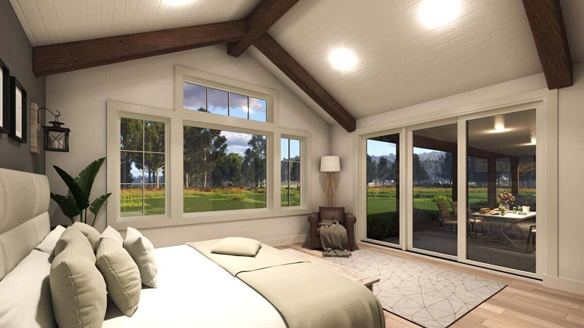 Primary bedroom with an upholstered bed and a cathedral ceiling accentuated with exposed beams.
