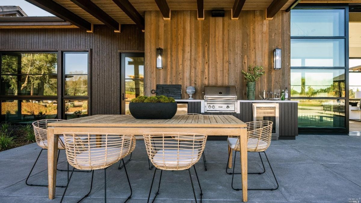 Outdoor kitchen with a grill and table and chairs.