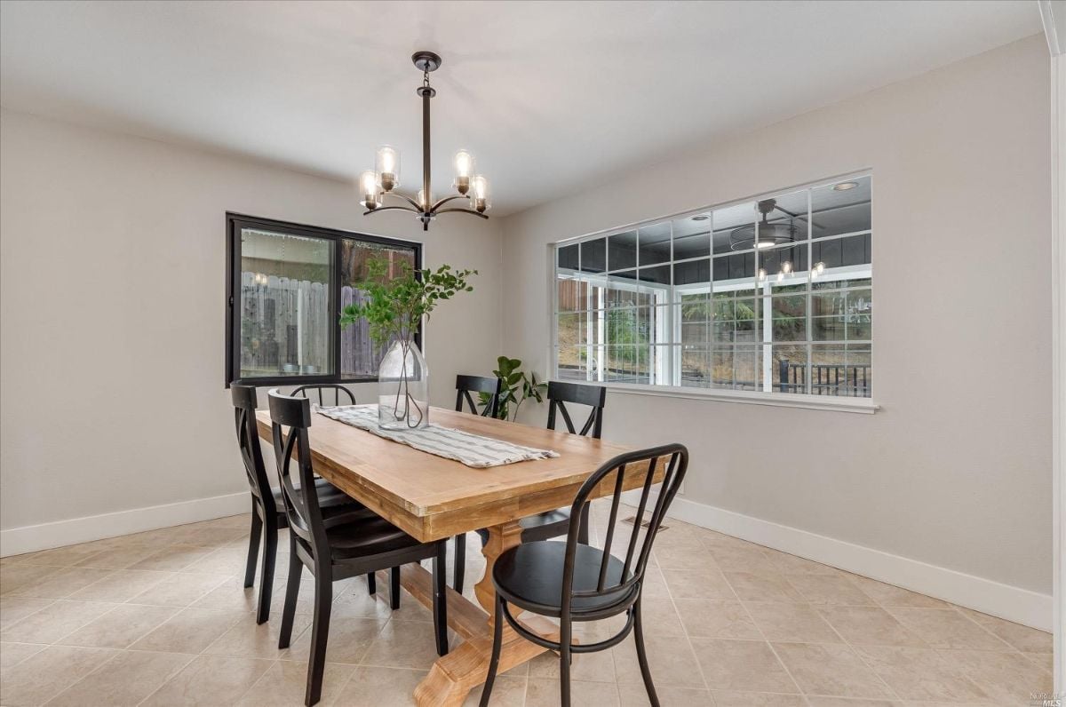 Dining room with wooden table, tile flooring, and chandelier.