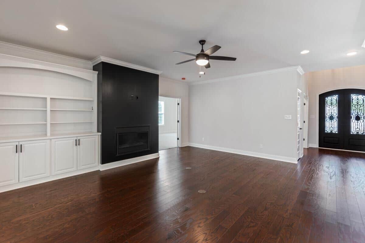 Family room with a fireplace, white built-ins, and hardwood flooring.