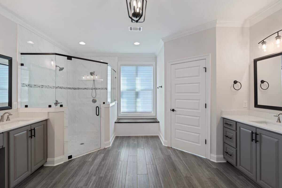 Primary bathroom with separate his and her sink vanities, a water closet, a tiled shower, and a window seat.