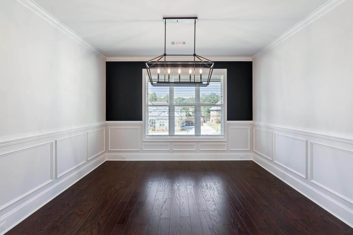 A trio of windows along with a linear chandelier brighten the dining room.