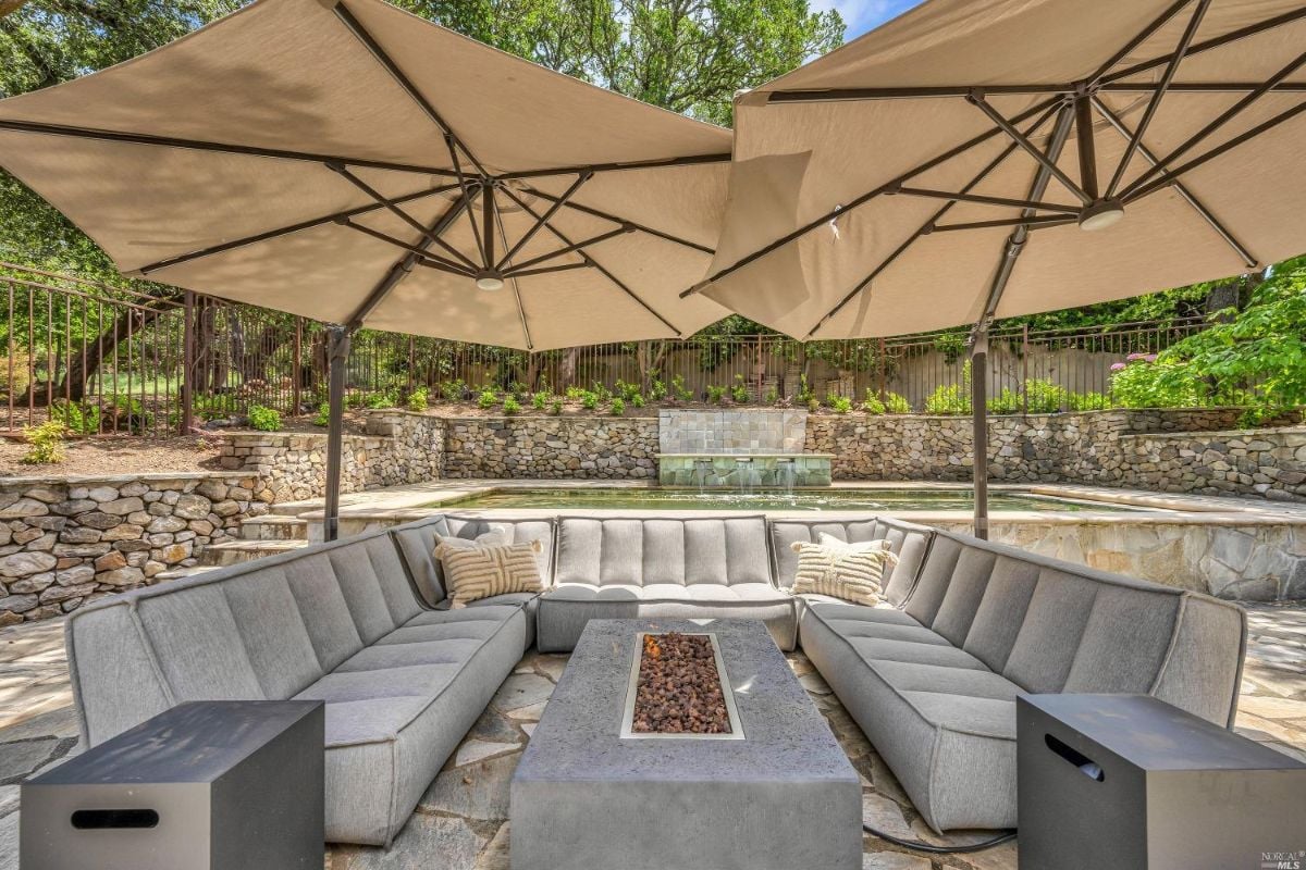 Patio with a fire pit, couches and a pool