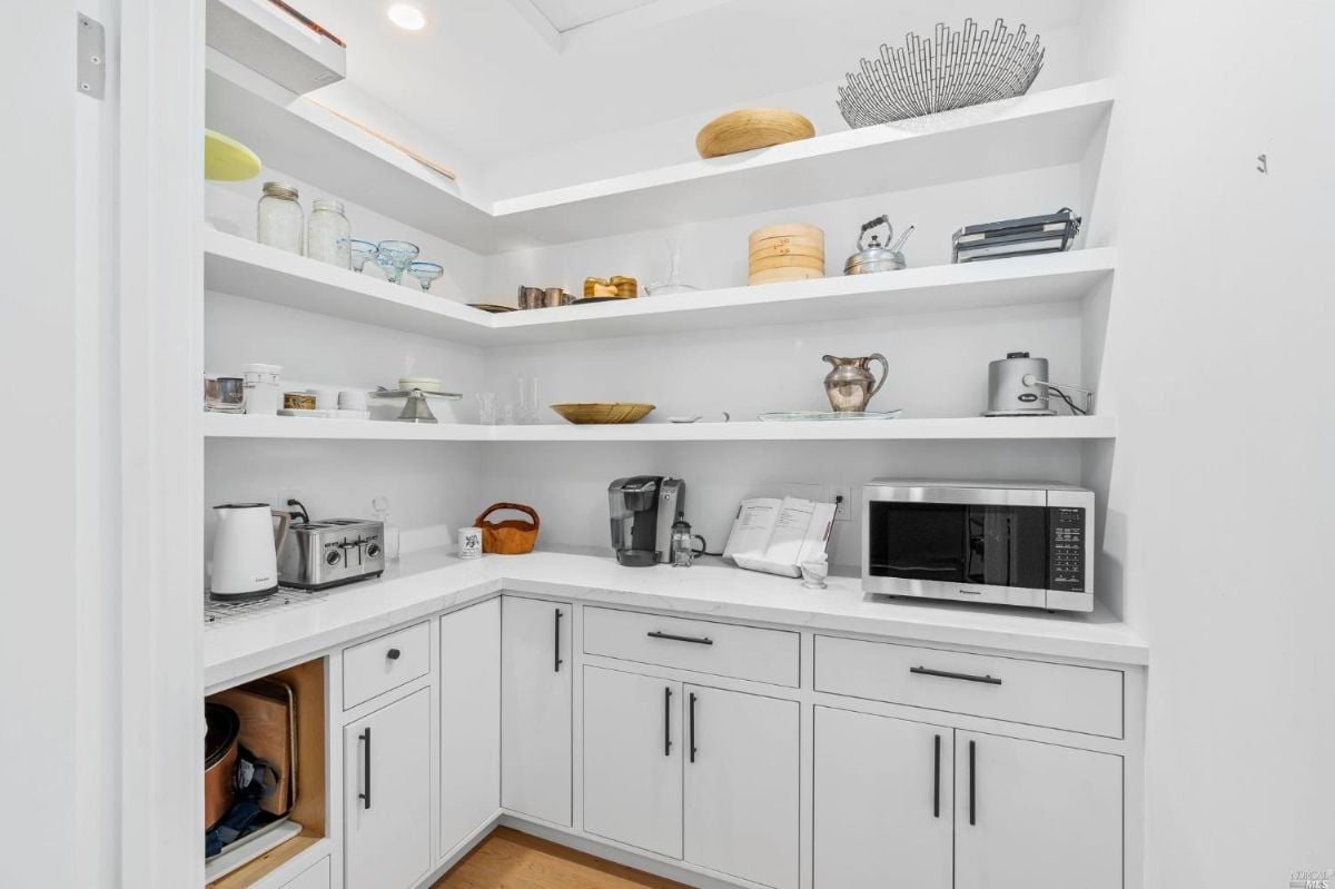 Pantry with white cabinets and white counter tops.