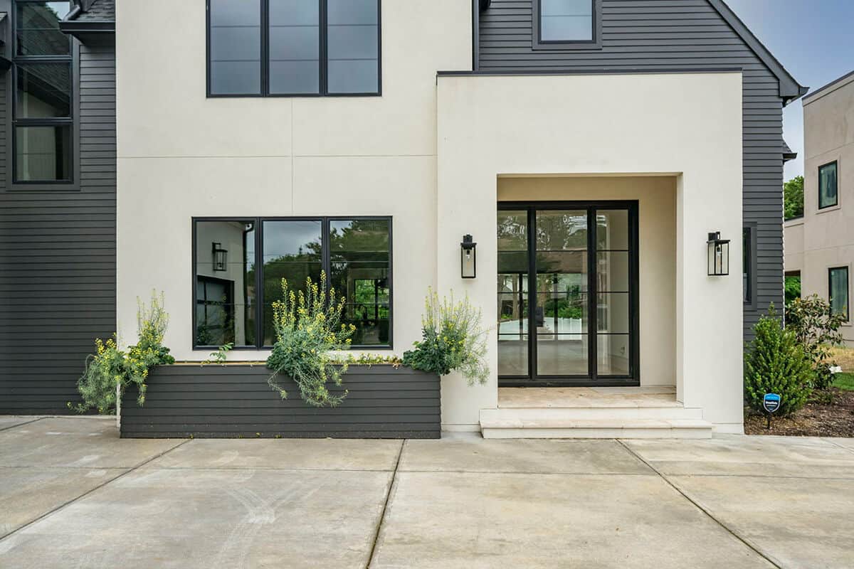 A closer look at the covered entry porch with a glass front door flanked by sidelights.