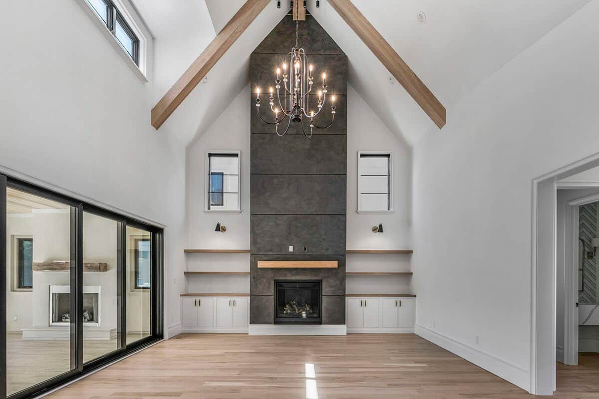 Gathering room with a fireplace, built-in cabinets and shelves, and a high cathedral ceiling lined with exposed beams.