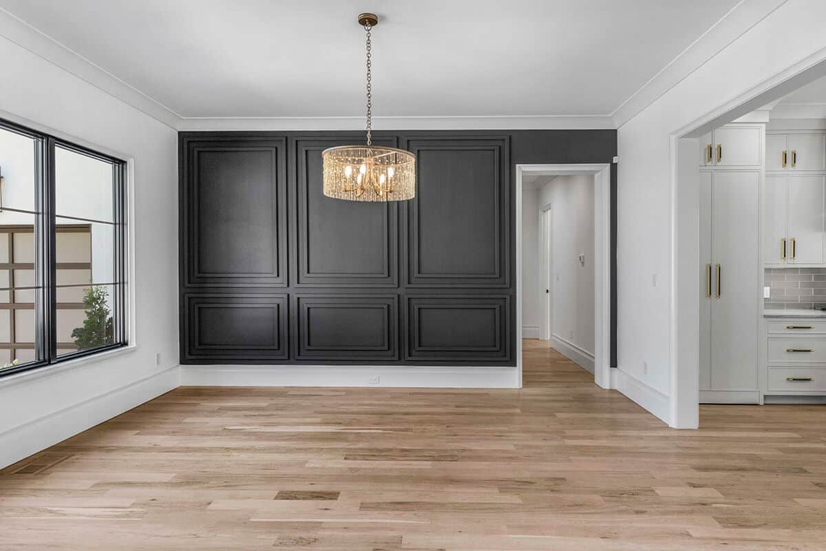 The formal dining room is decorated with a black wainscoted wall and a classy chandelier.