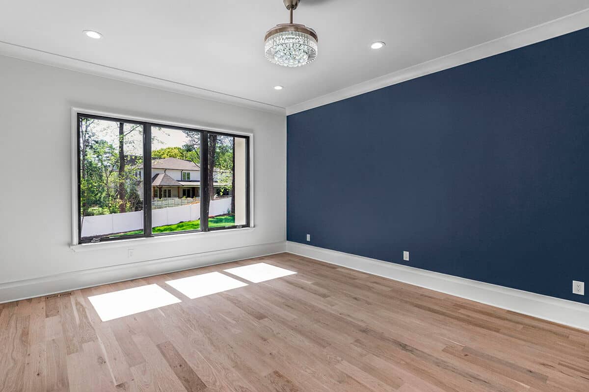 Primary bedroom with a deep blue accent wall and light hardwood flooring.