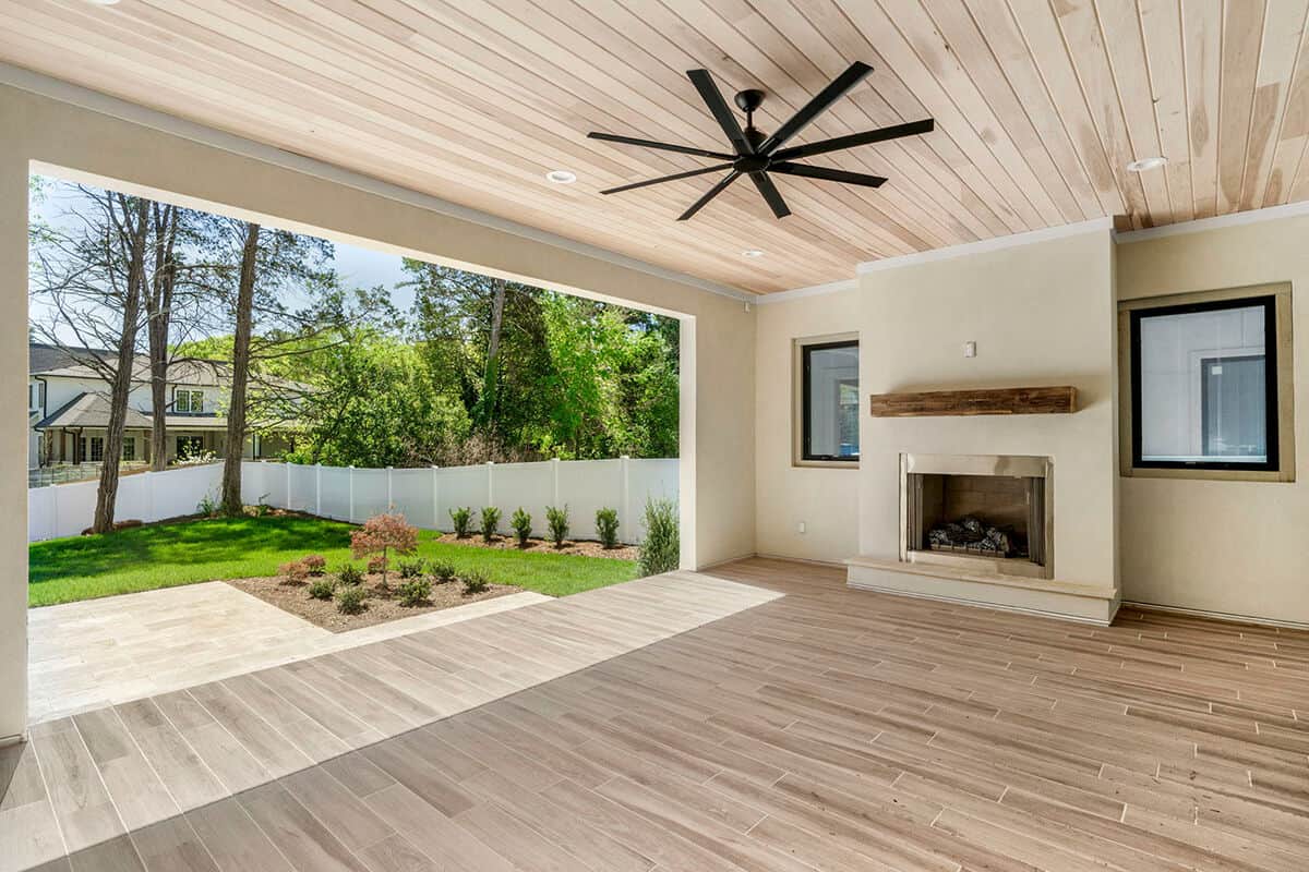 The covered terrace features an outdoor fireplace and a wood-paneled ceiling that mirrors the hardwood floor.