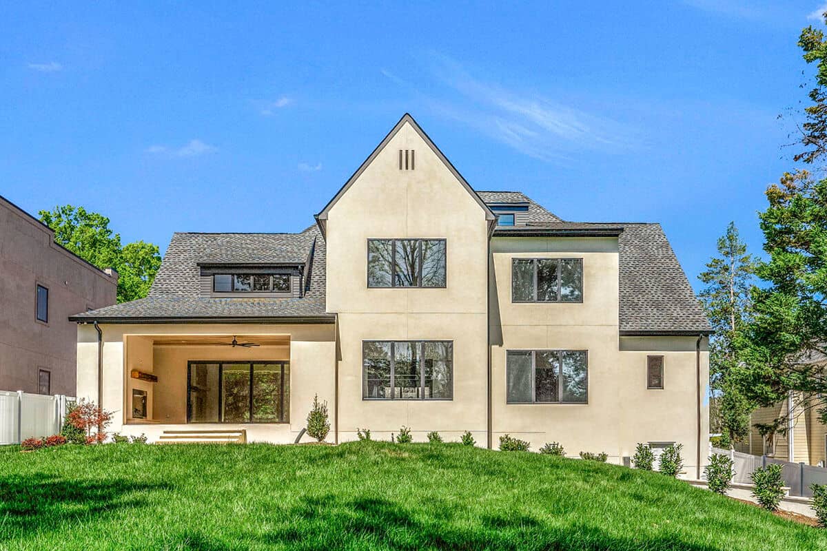 View of the house from the backyard showcasing its covered terrace and large windows.