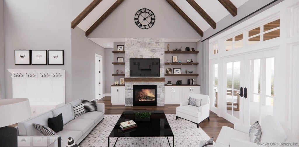 Great room with modern seats, a metal coffee table, and a stone fireplace under a vaulted ceiling with exposed beams.