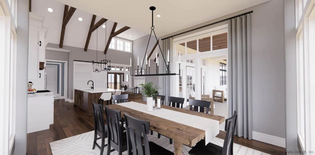 Dining area with black chairs and a rustic table topped with a wrought iron chandelier.