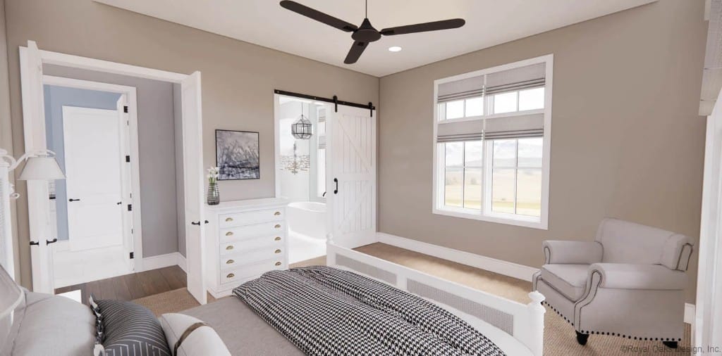 Primary bedroom with a white bed, a cushioned armchair, and an ensuite bath with a sliding barn door.