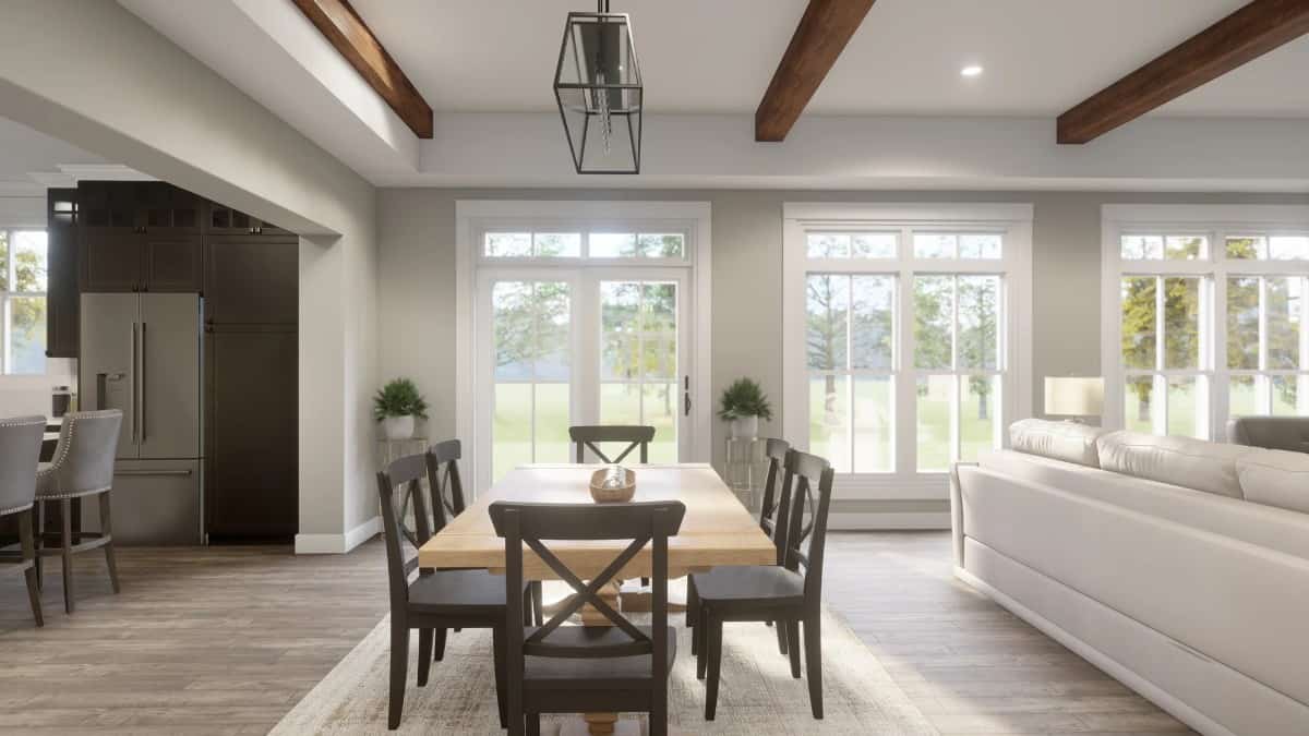 A linear chandelier and large windows illuminate the combined dining and living rooms.
