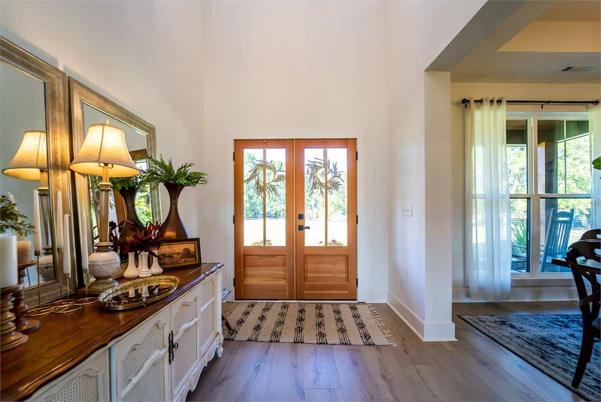 The foyer has a French entry door and a wooden console table topped with large mirrors.