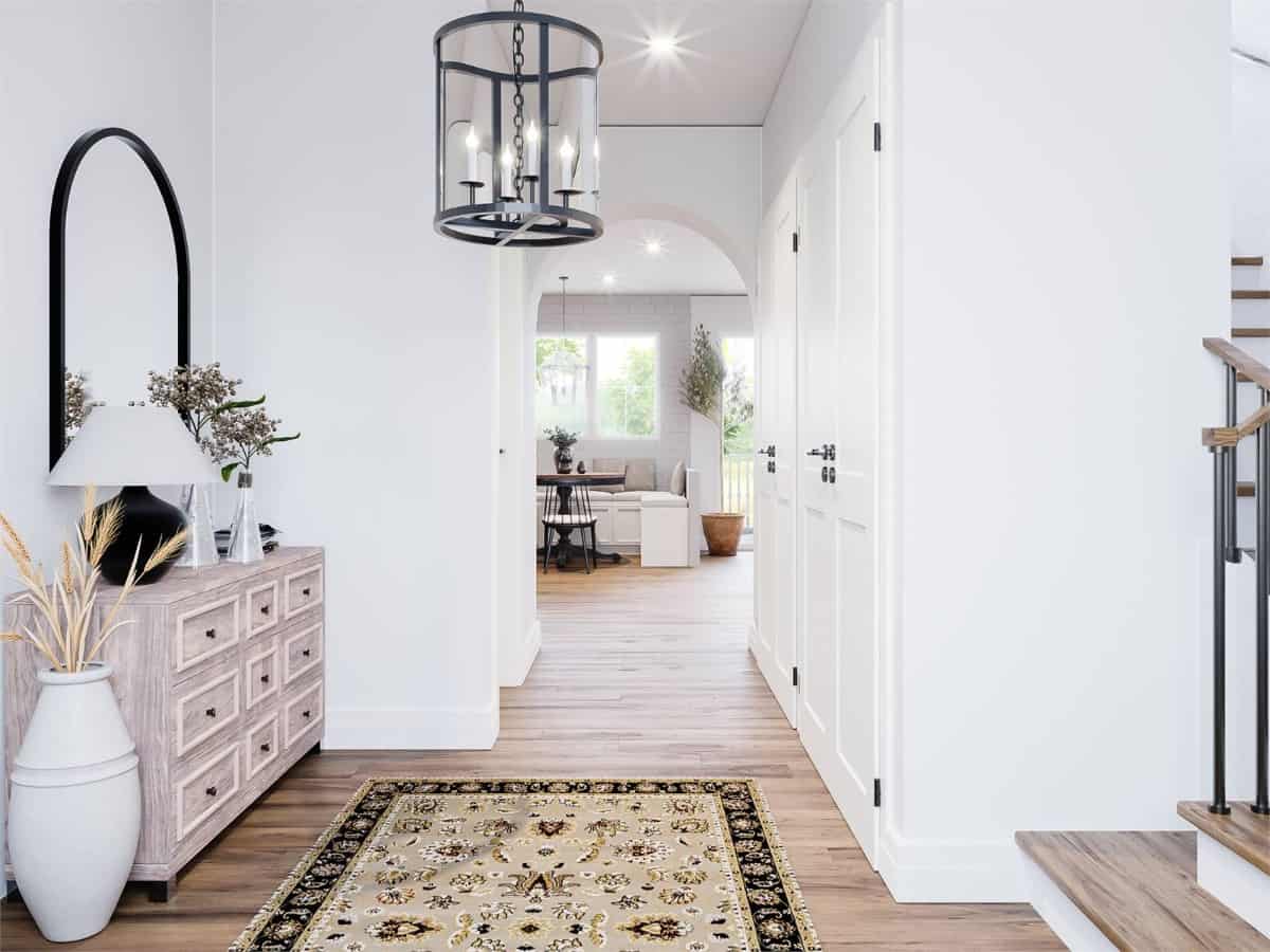 The foyer has a light wood console table, a staircase, and an archway leading to the open living space.