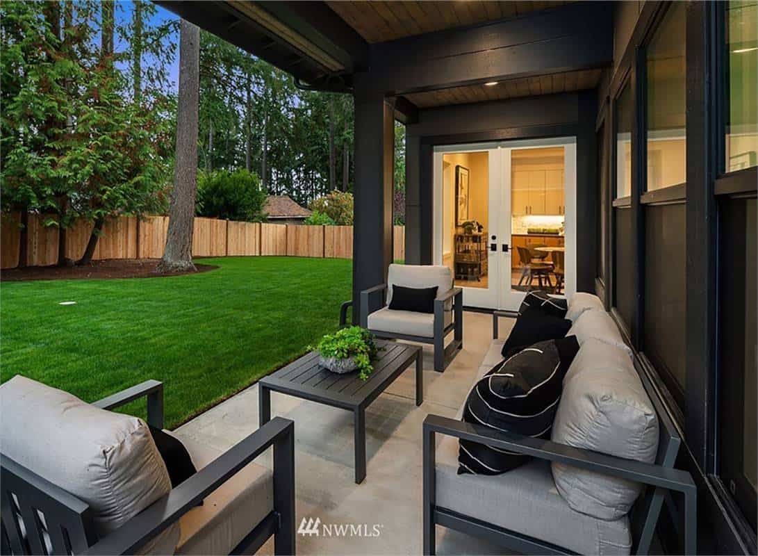 Covered patio with sliding glass doors, cushioned, seats, and a matching coffee table over the concrete flooring.