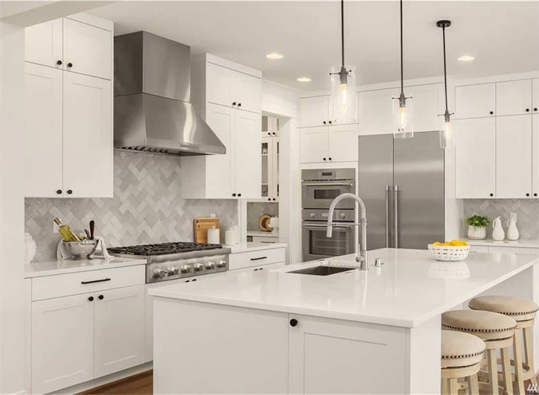 Kitchen with modern appliances, white cabinetry, and a breakfast island.