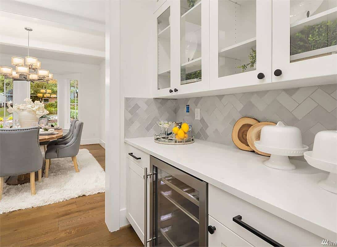 Butler's pantry with white and glass-front cabinets, a wine fridge, and a view of the dining room.