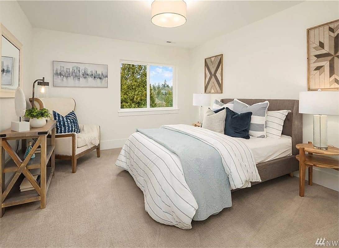 Second bedroom with wingback chair, an upholstered bed, and wooden tables over the carpeted floor.