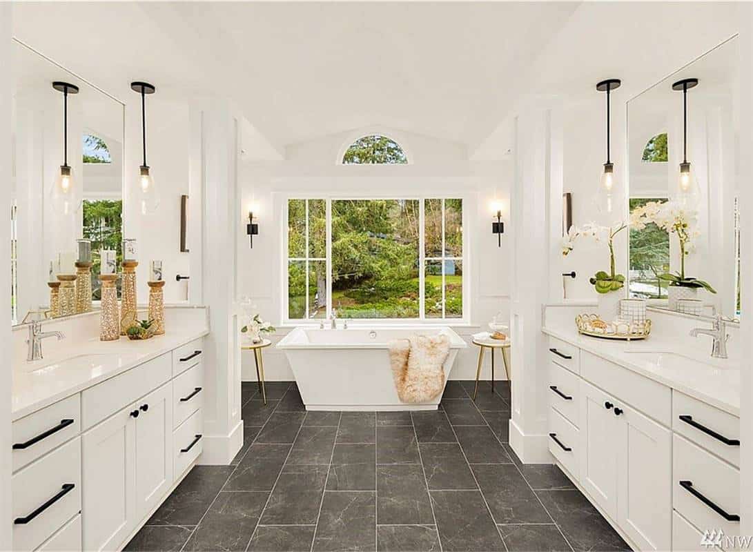 Primary bathroom with his and her sink vanities and a soaking tub brightened by huge windows.