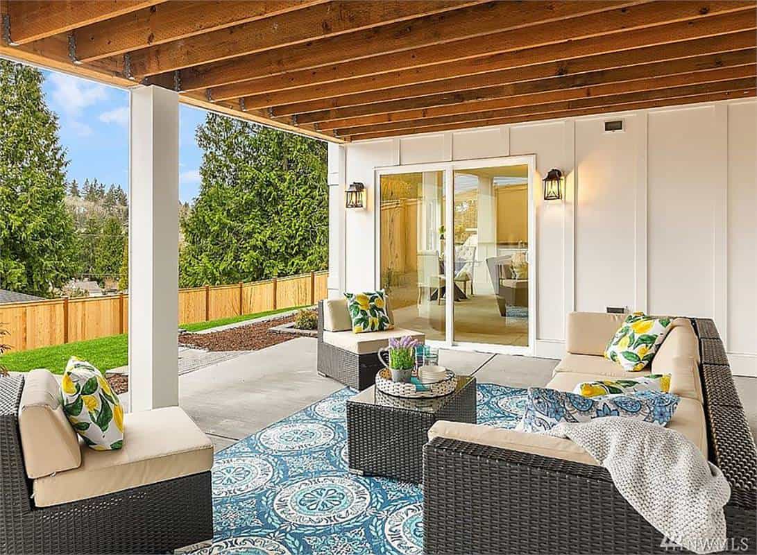 Covered patio with cushioned wicker seats and a matching coffee table under the beamed ceiling.