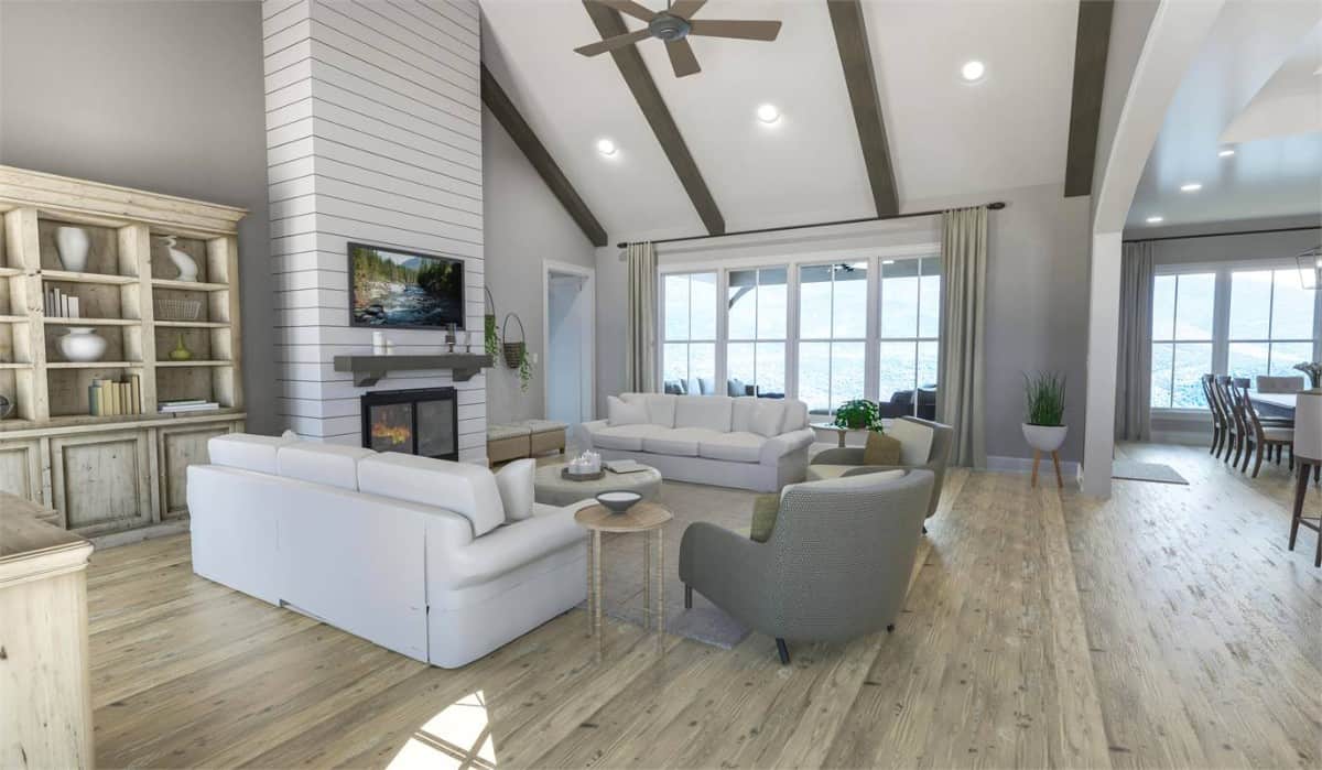 Living room with neutral seats, a fireplace with a TV on top, and a vaulted ceiling lined with exposed beams.