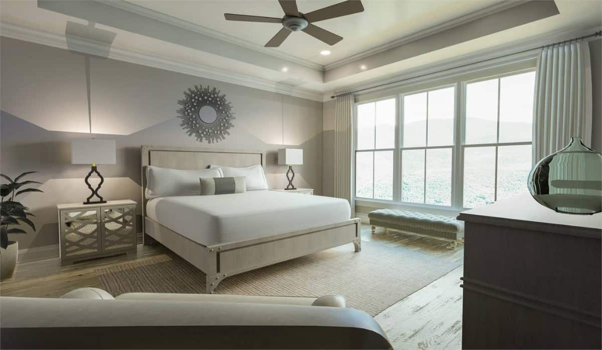 Primary bedroom with a tray ceiling, a wooden bed, and a tufted bench against the large windows.