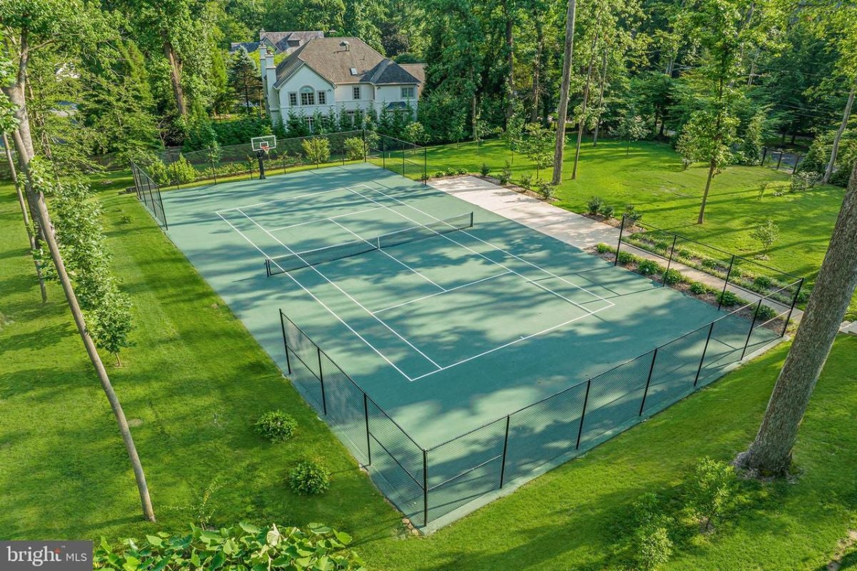 A tennis court surrounded by trees and grass.