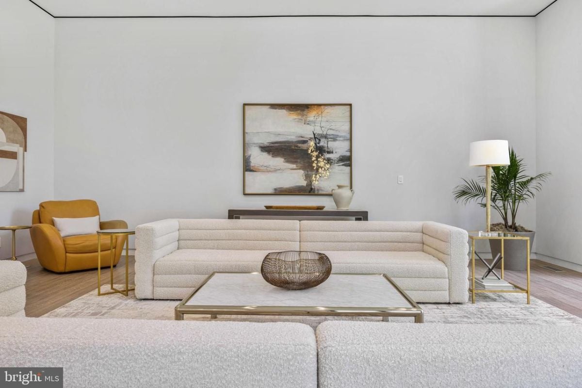 A living room features a white couch and a large painting.