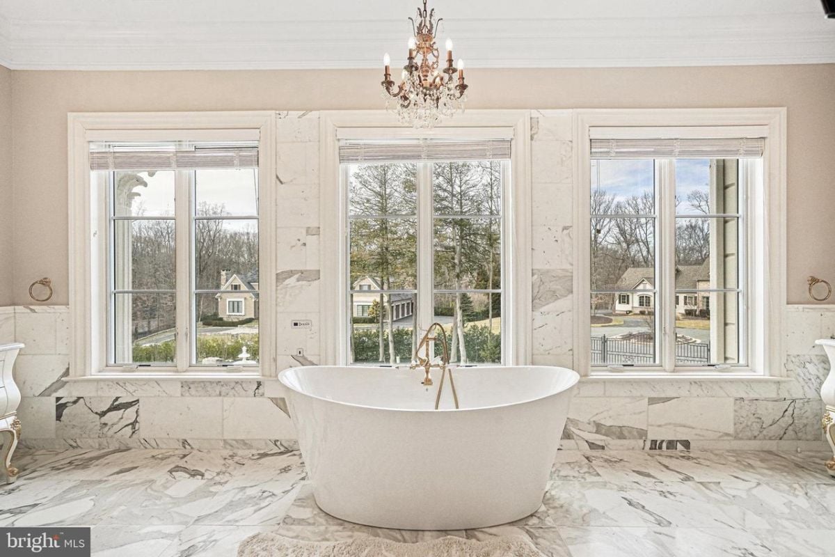 A large bathroom with marble floors and a large tub.