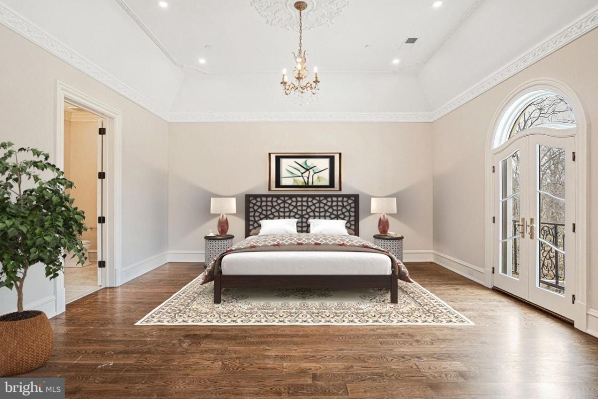 A bedroom with a large bed and a chandelier.