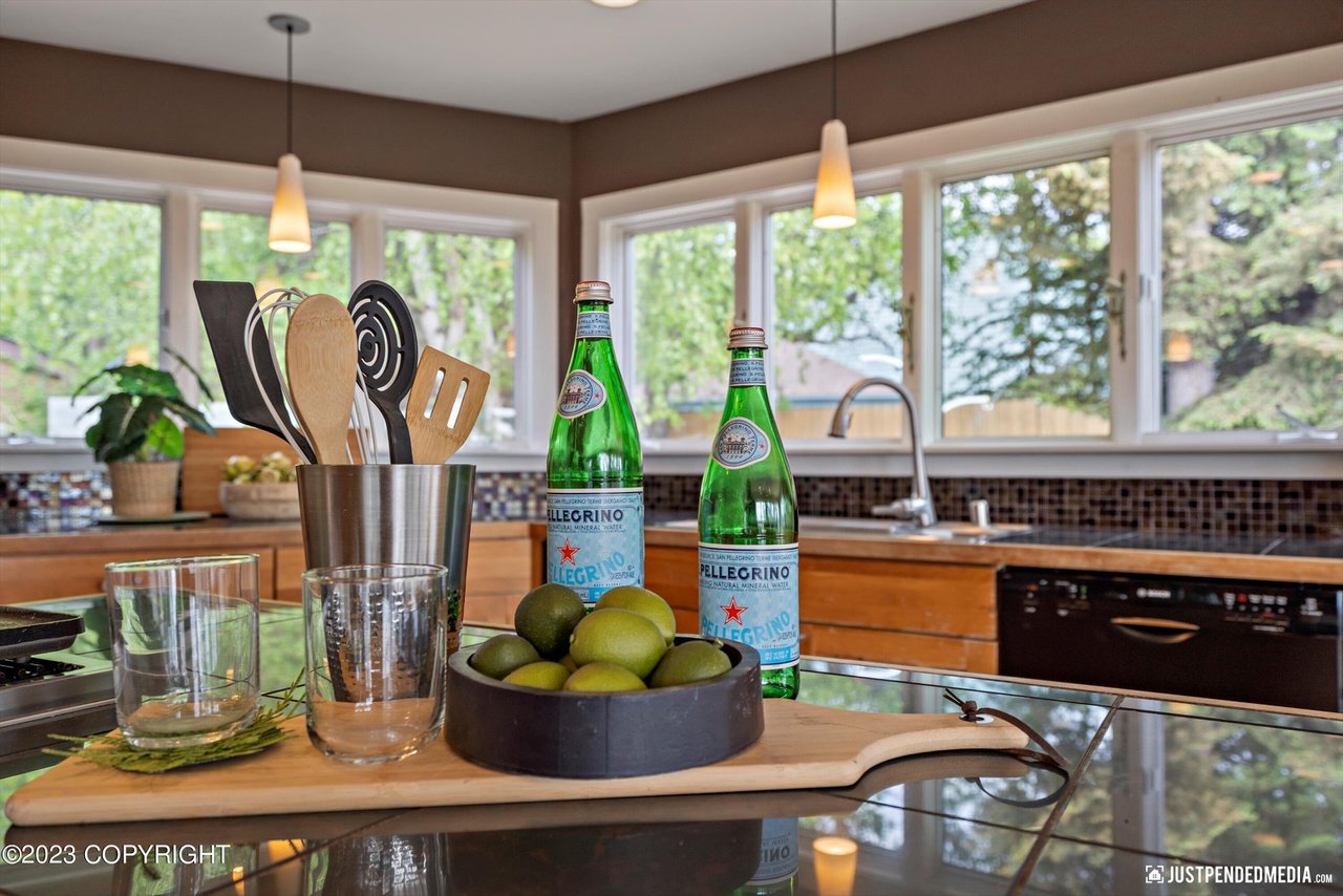 A kitchen counter with a bowl of fruit and a bottles of water.