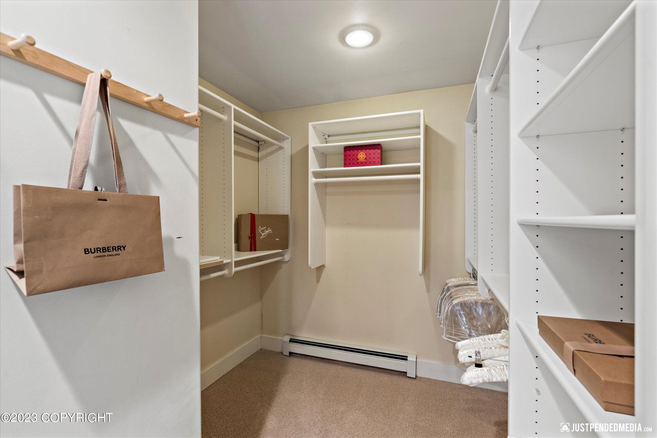 Walk in closet with a white wall and shelves.