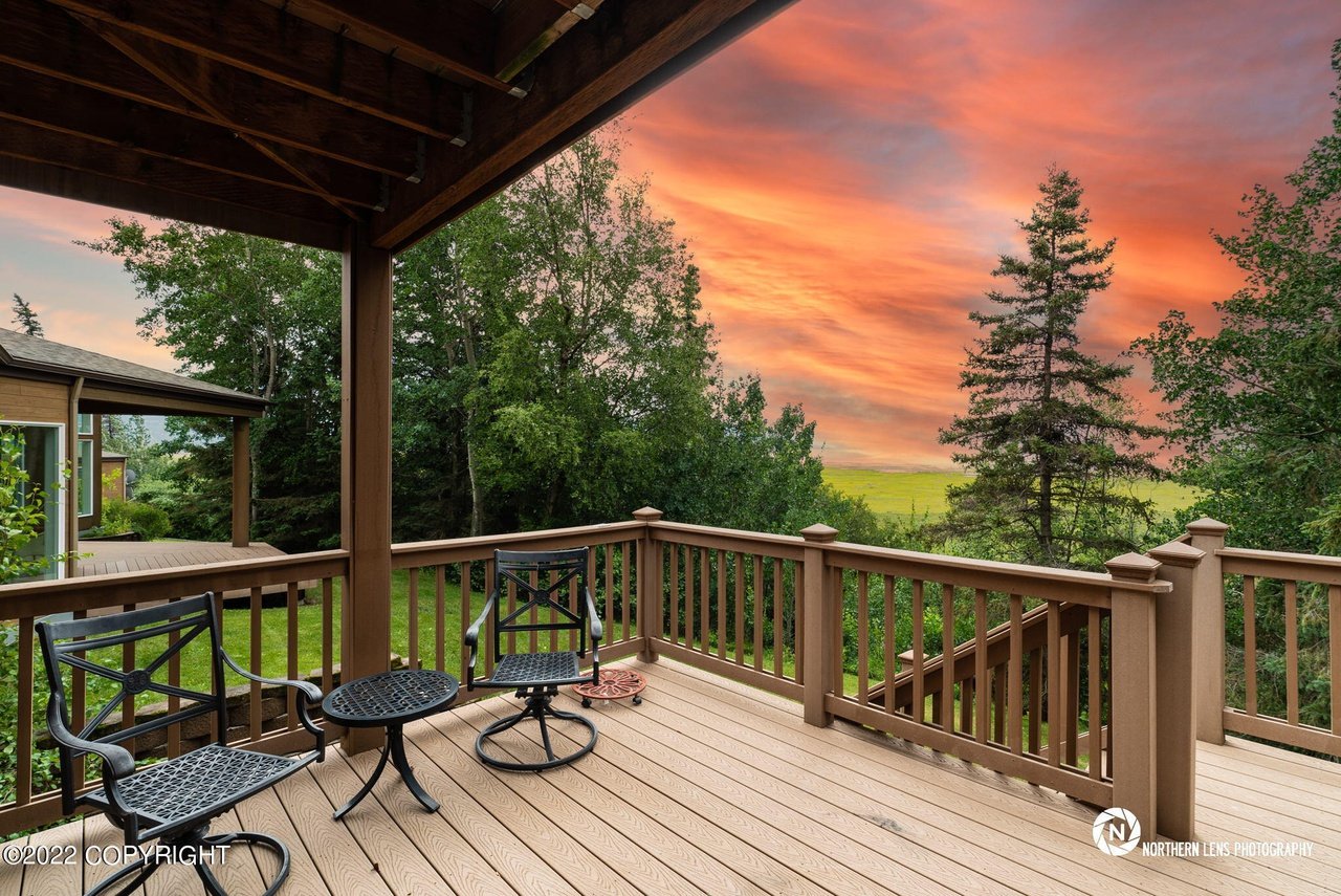 A deck with chairs and a view of the sunset.