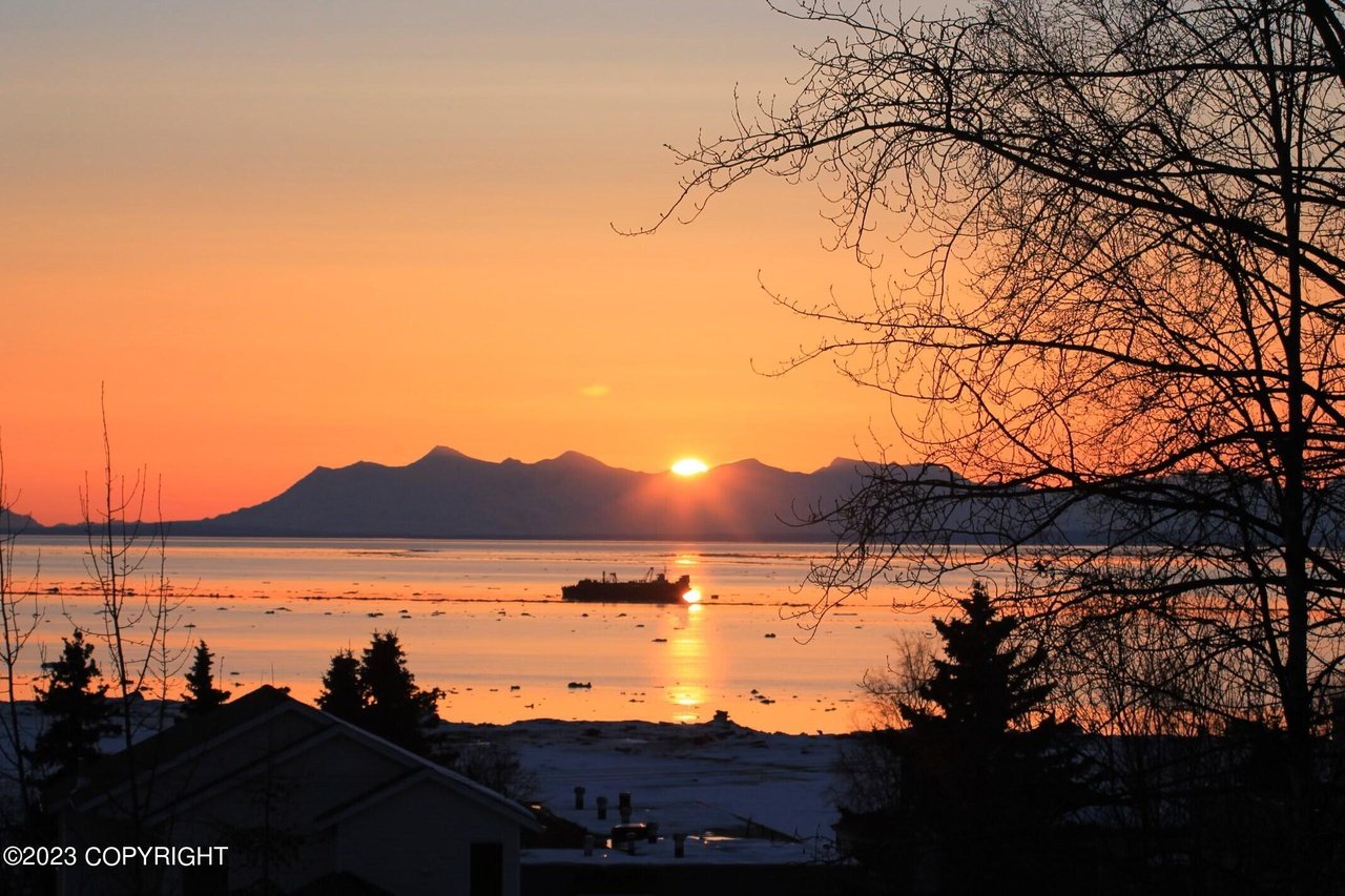 A view from the backyard deck with a sunset over the water.