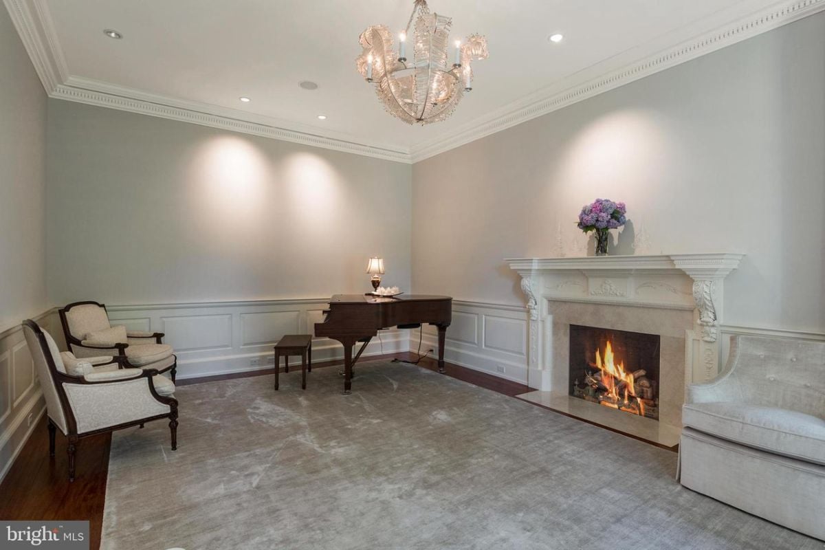 A living room with a piano, fireplace and chairs.
