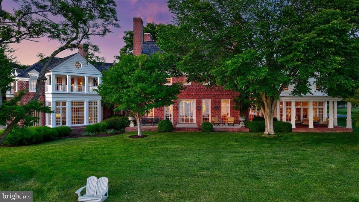 Backyard of the house with a large lawn and trees.