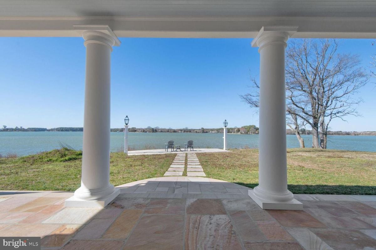 A large porch with columns and a view of the water.