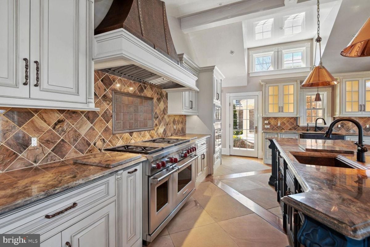 A kitchen with marble counter tops and white cabinets.