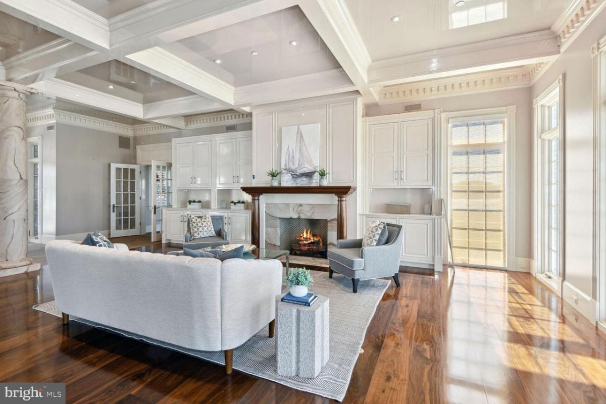 A living room with a fireplace and white furniture.
