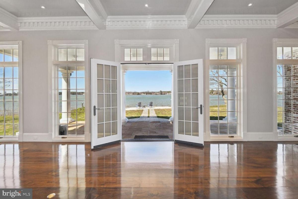 A large open living room with a large glass door leading to the lake.