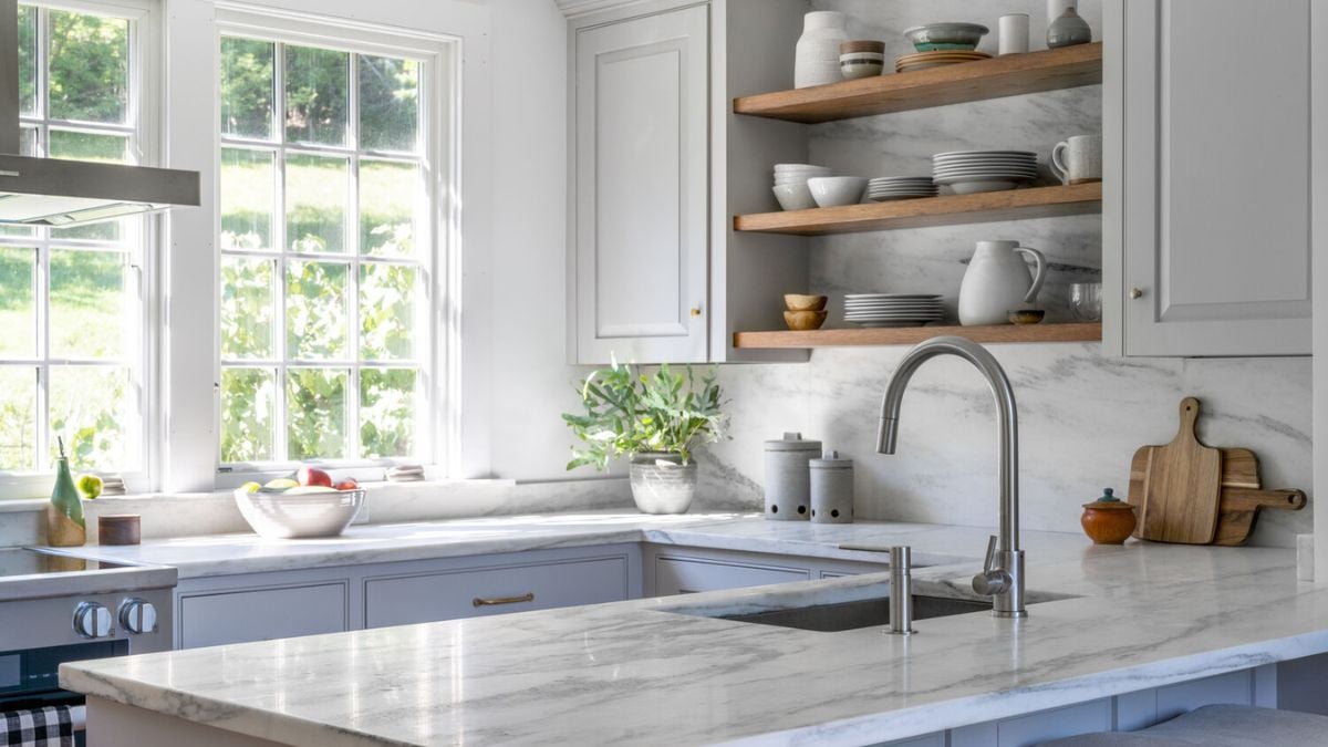 A kitchen with white cabinets and marble counter tops